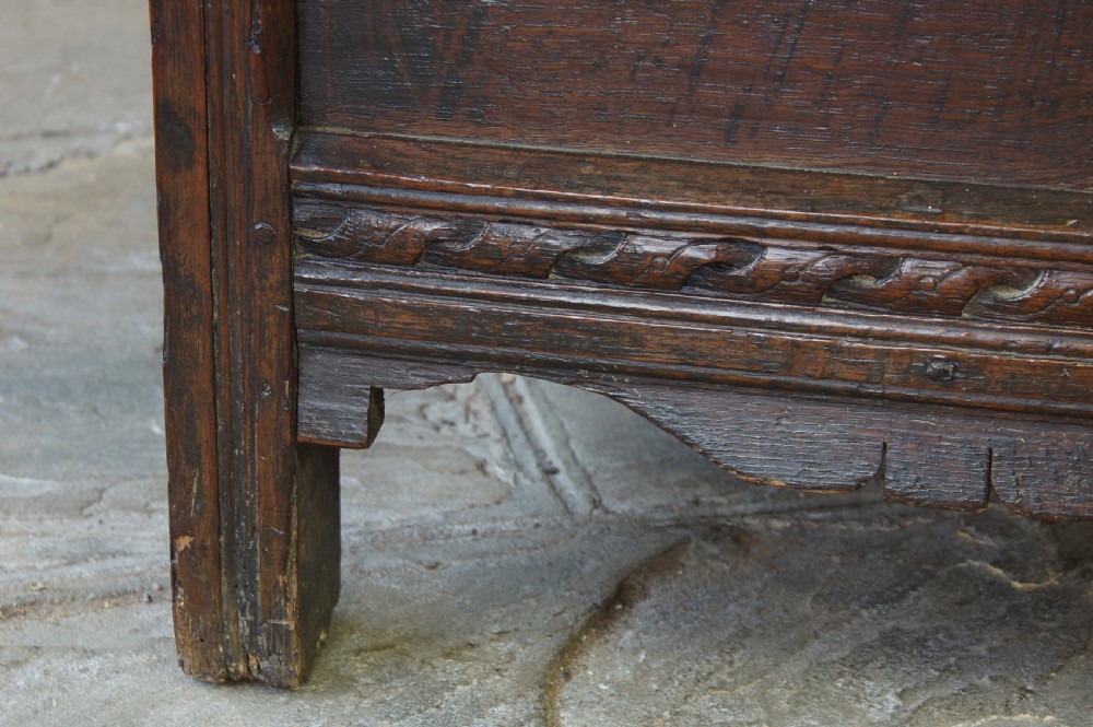 A 17th-century dark oak coffer featuring carved floral panel decoration, a lunette frieze, and a twin-panelled hinged lid. View II