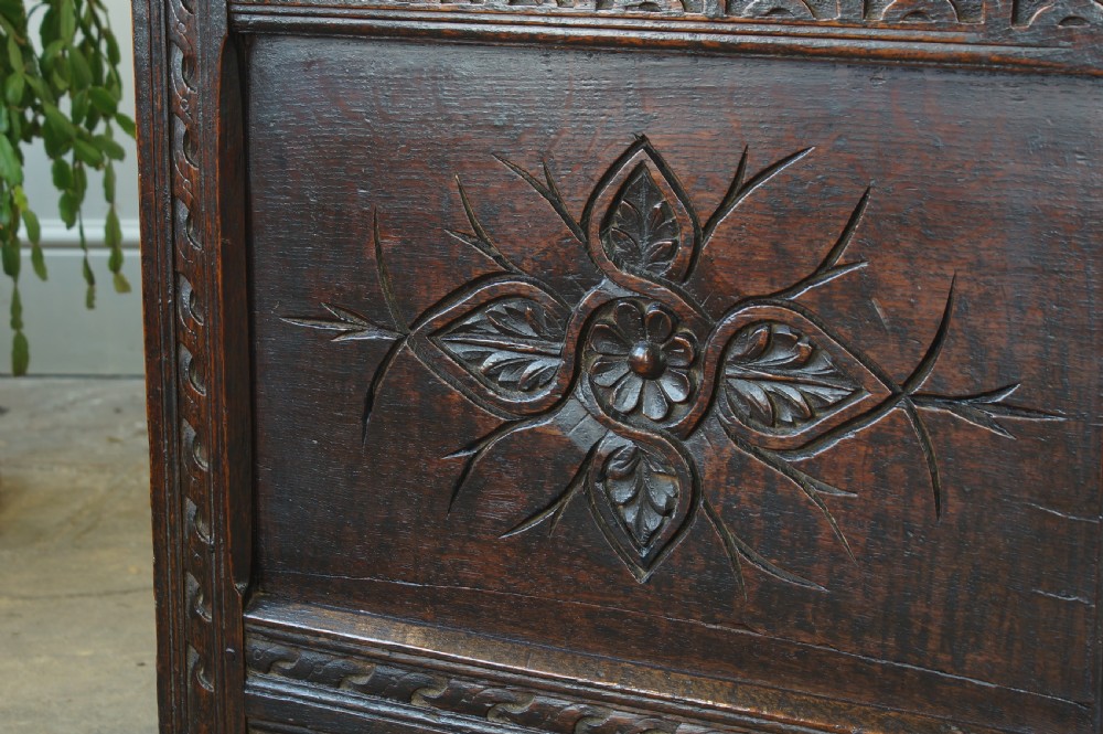 A 17th-century dark oak coffer featuring carved floral panel decoration, a lunette frieze, and a twin-panelled hinged lid. View VII