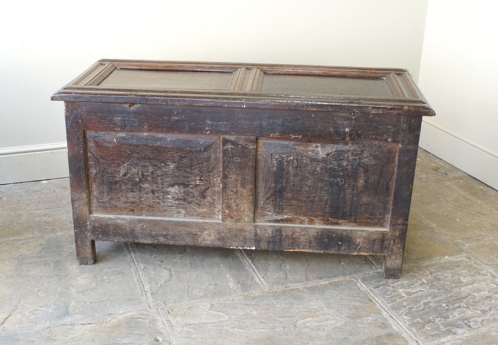 A 17th-century dark oak coffer featuring carved floral panel decoration, a lunette frieze, and a twin-panelled hinged lid. View XVII