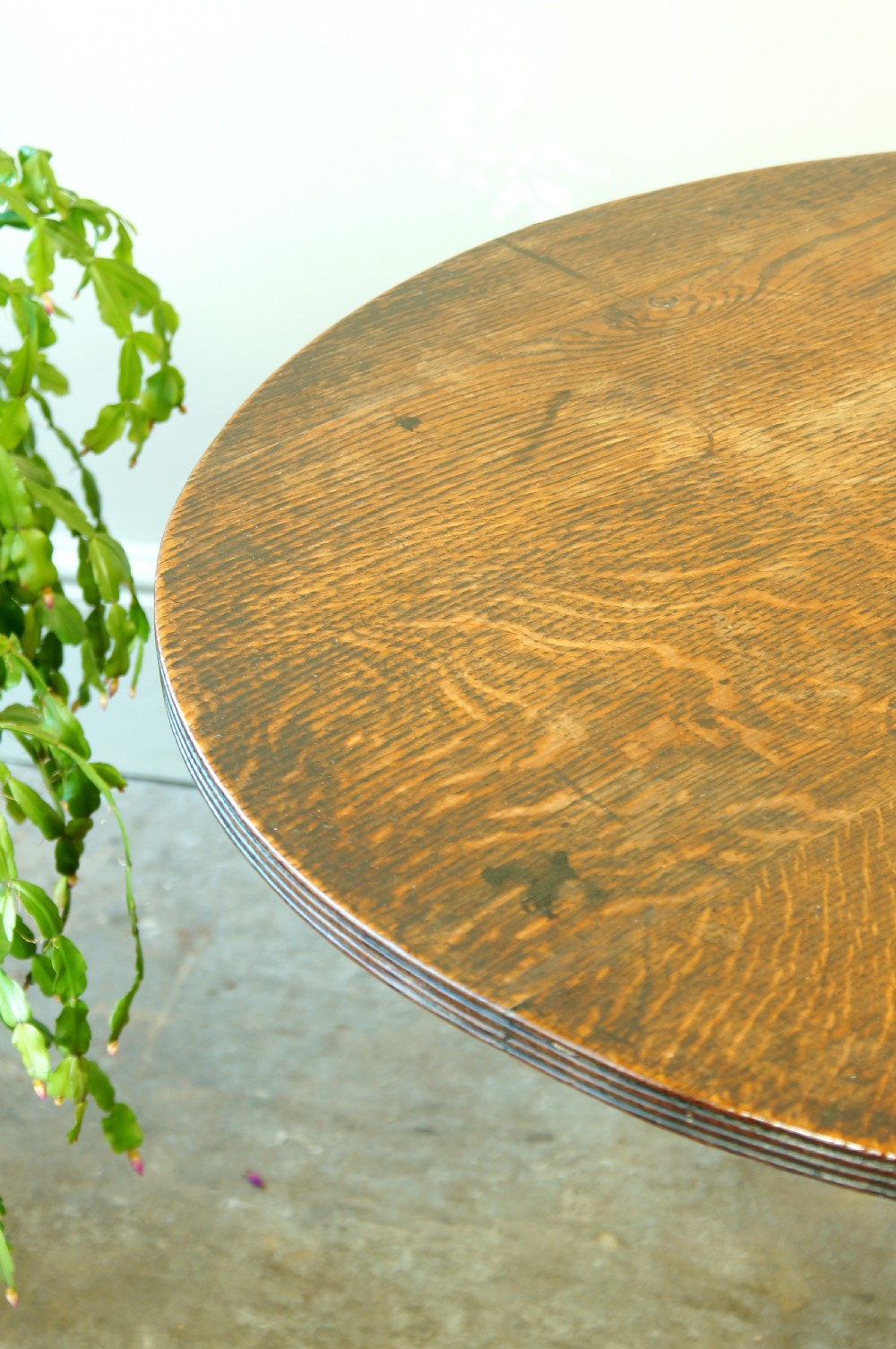 A Georgian oak tilt-top tripod table with a circular top shown in a vertical position, supported by a turned column and three splayed cabriole legs. View VI
