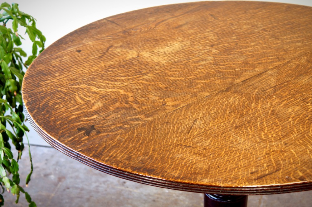 A Georgian oak tilt-top tripod table with a circular top shown in a vertical position, supported by a turned column and three splayed cabriole legs. View XII