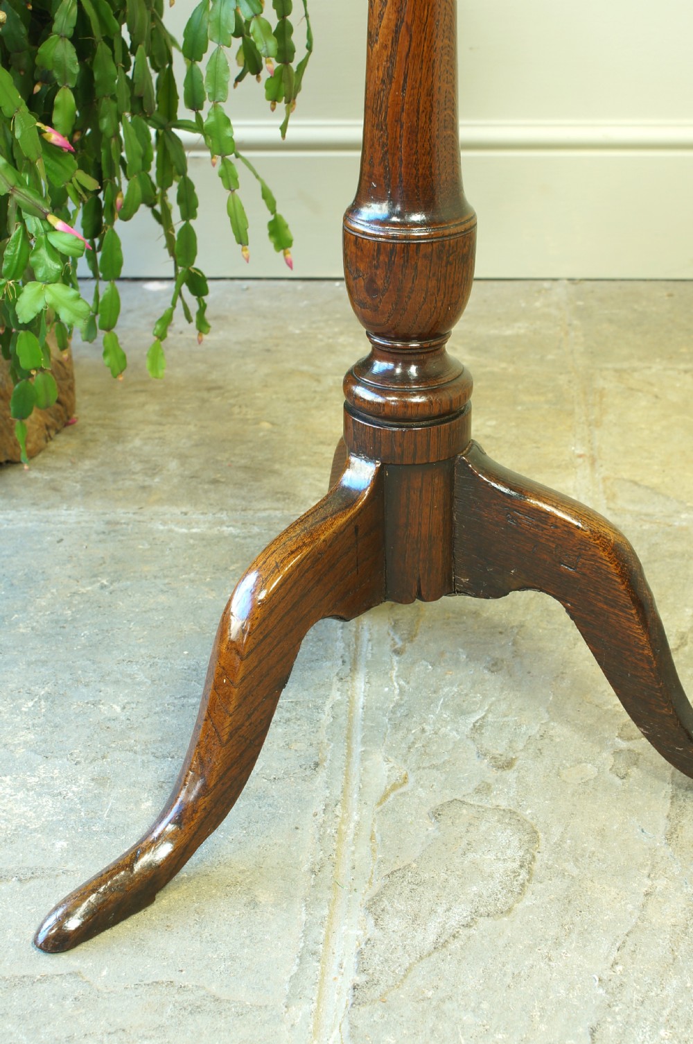 A small circular 18th-century oak tripod table with a turned central column and three curving legs, viewed from above against a neutral background. View VI