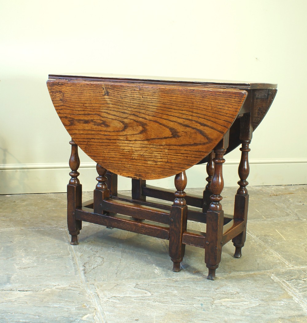 A small 17th-century oak gateleg table with two drop leaves, turned legs, and lower box stretchers. View X