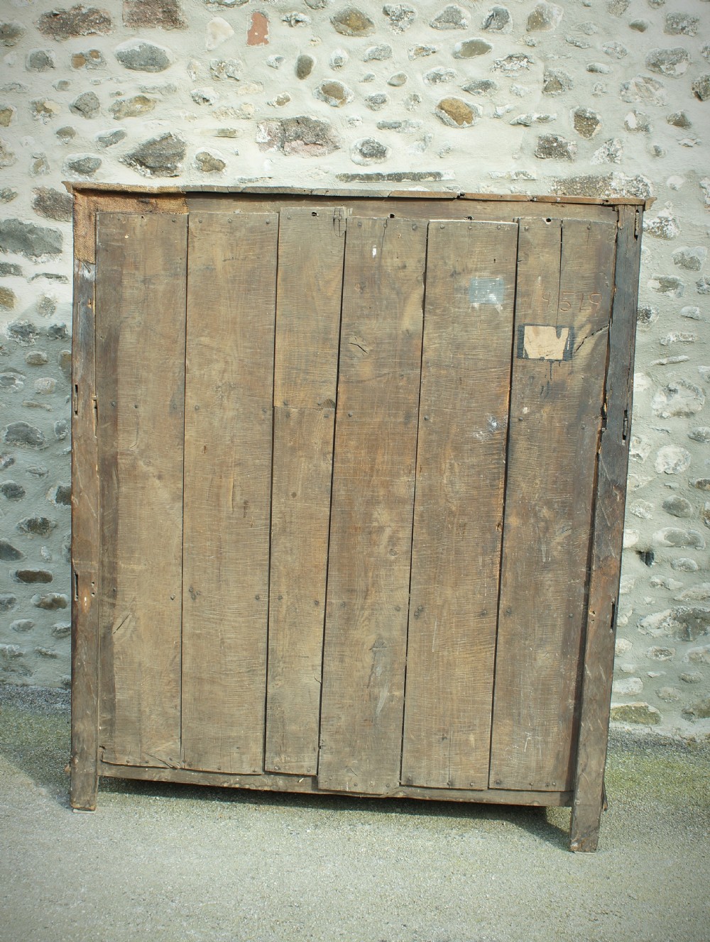 A dark brown seventeenth-century carved oak press cupboard featuring symmetrical panel doors and geometric detailing. View VI