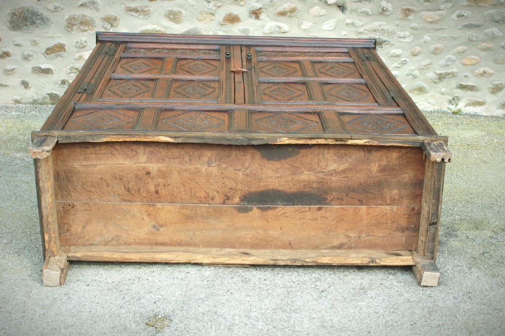 A dark brown seventeenth-century carved oak press cupboard featuring symmetrical panel doors and geometric detailing. View VII