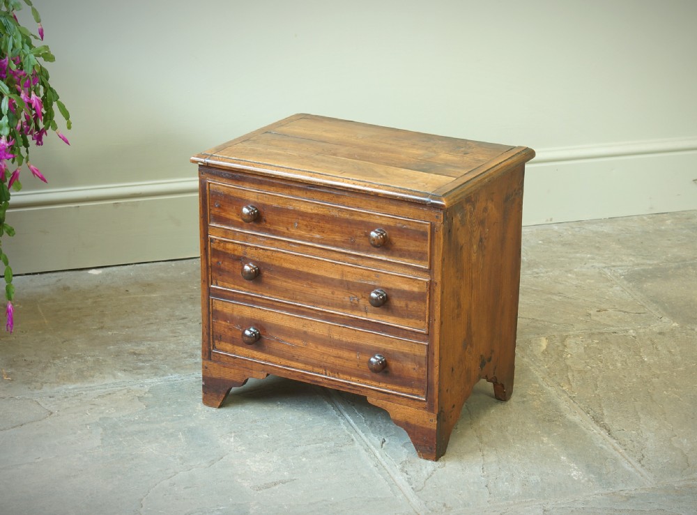 A Georgian plumwood close stool disguised as a small three-drawer chest with turned wooden knobs and bracket feet. View VII