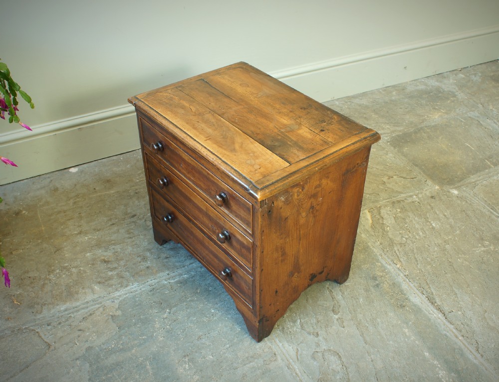 A Georgian plumwood close stool disguised as a small three-drawer chest with turned wooden knobs and bracket feet. View III