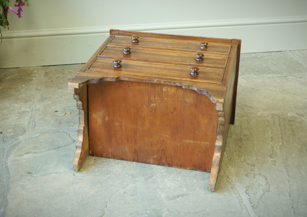 A Georgian plumwood close stool disguised as a small three-drawer chest with turned wooden knobs and bracket feet. View X