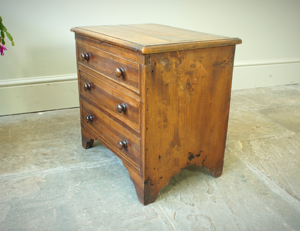 A Georgian plumwood close stool disguised as a small three-drawer chest with turned wooden knobs and bracket feet. View XI
