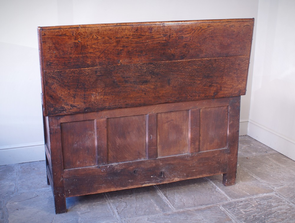 A 17th-century dark oak mule chest featuring carved friezes, three inlaid marquetry front panels with bird motifs, and two lower drawers with brass drop handles. View X