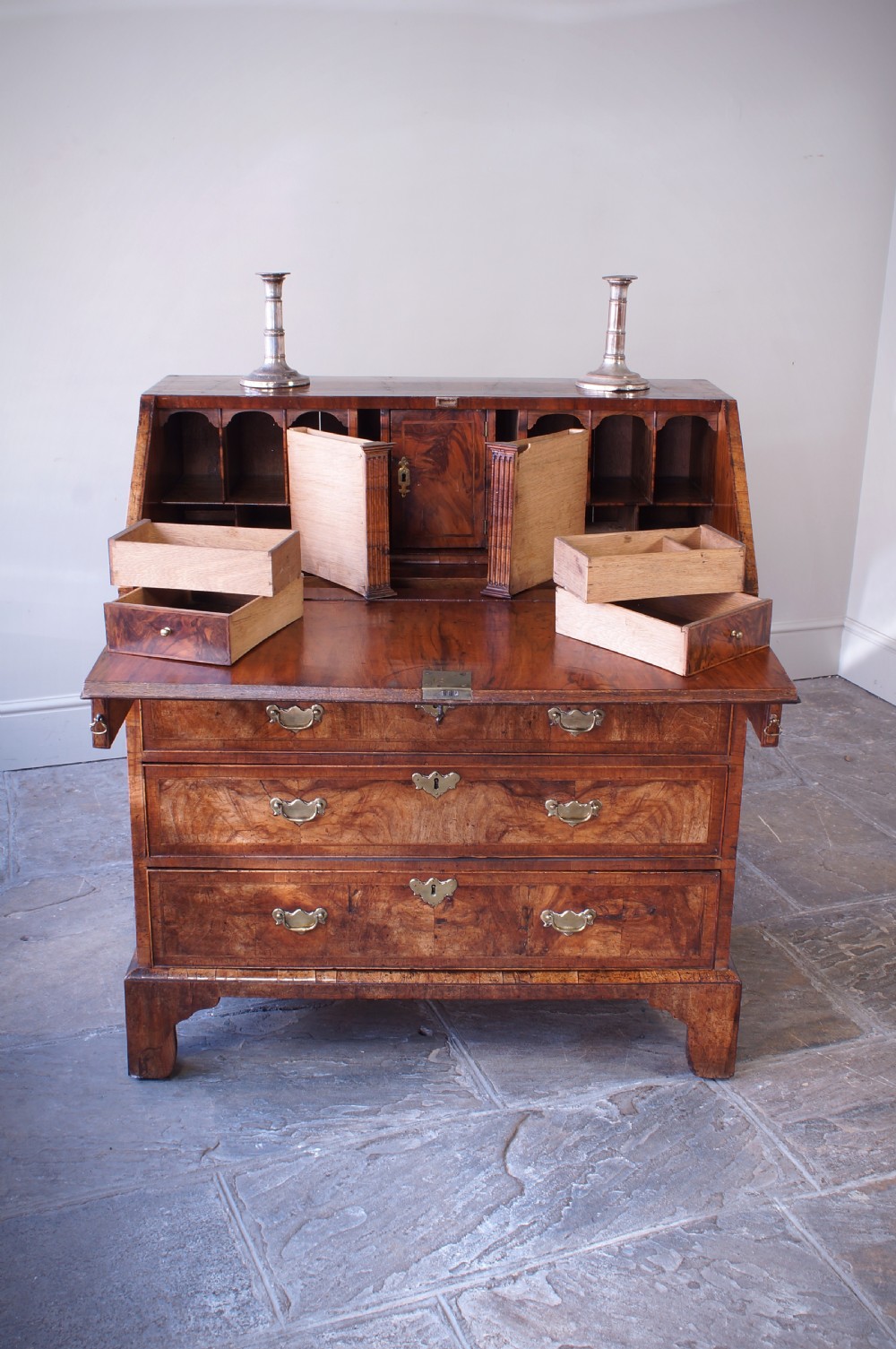 An 18th-century George II walnut bureau featuring a slant-front lid above four graduated drawers with brass handles, supported by bracket feet. View VI