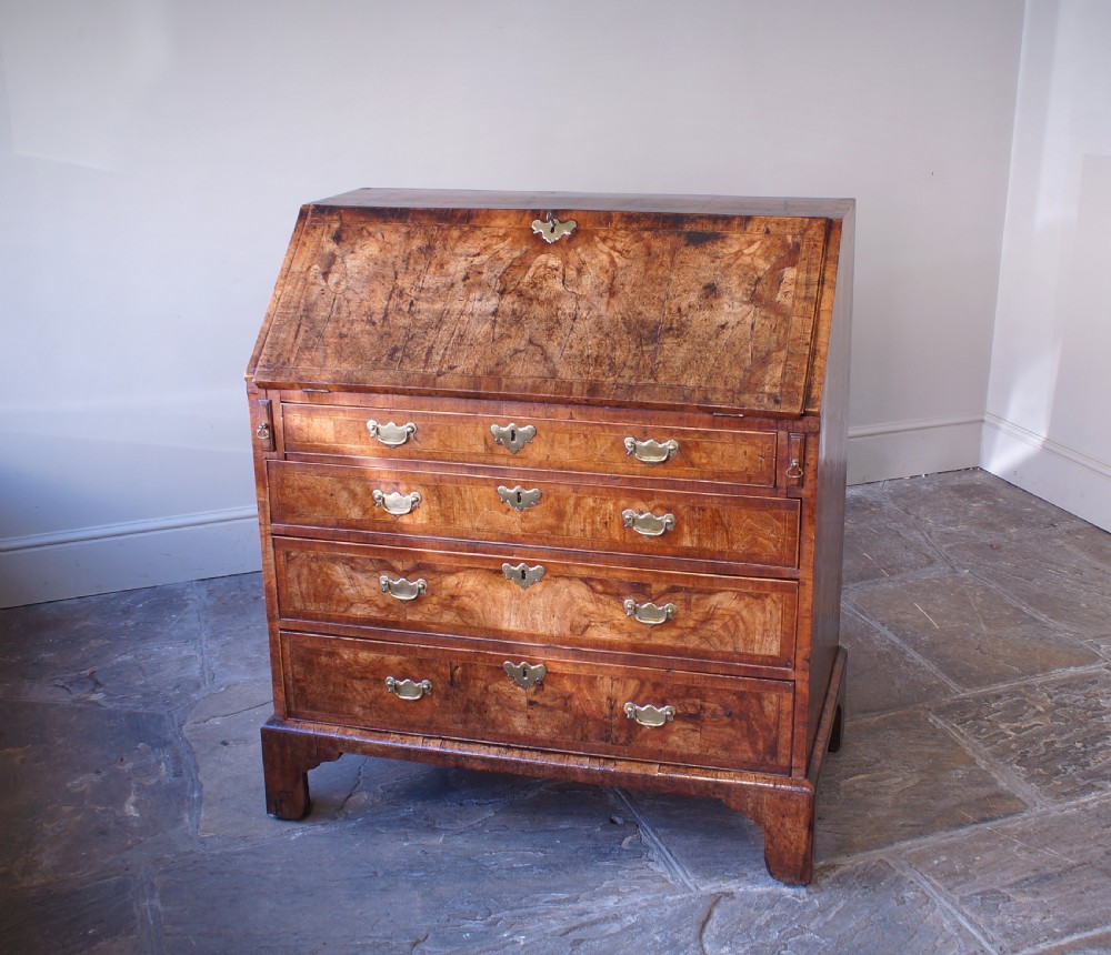 An 18th-century George II walnut bureau featuring a slant-front lid above four graduated drawers with brass handles, supported by bracket feet. View VIII
