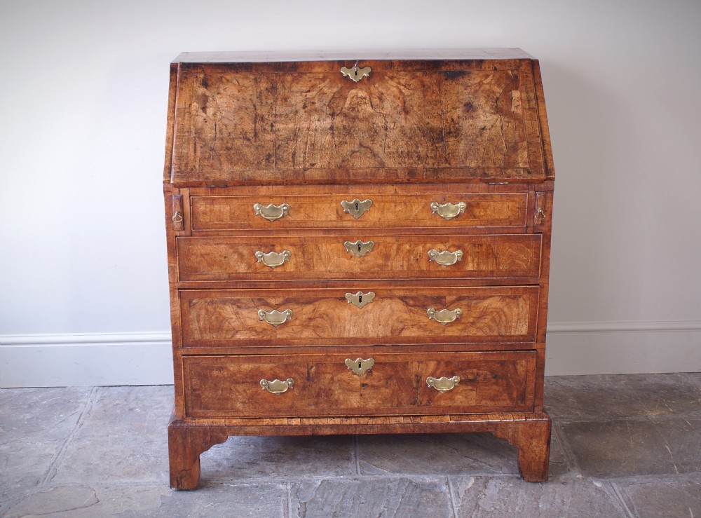 An 18th-century George II walnut bureau featuring a slant-front lid above four graduated drawers with brass handles, supported by bracket feet. View X