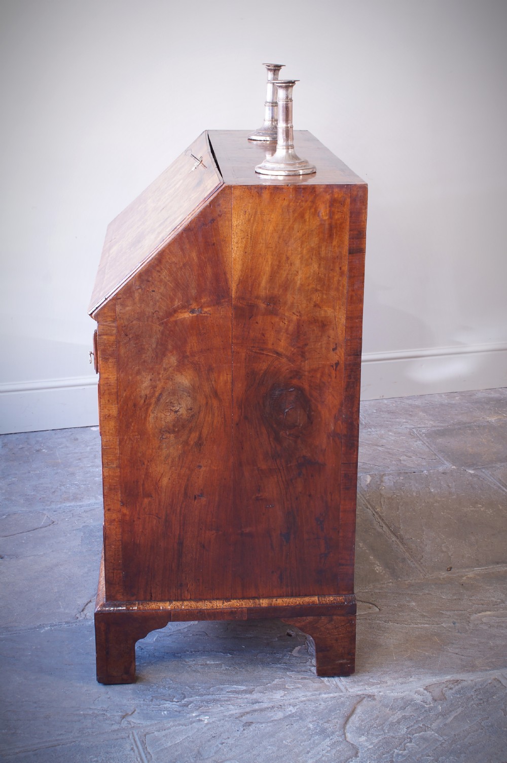 An 18th-century George II walnut bureau featuring a slant-front lid above four graduated drawers with brass handles, supported by bracket feet. View XVI