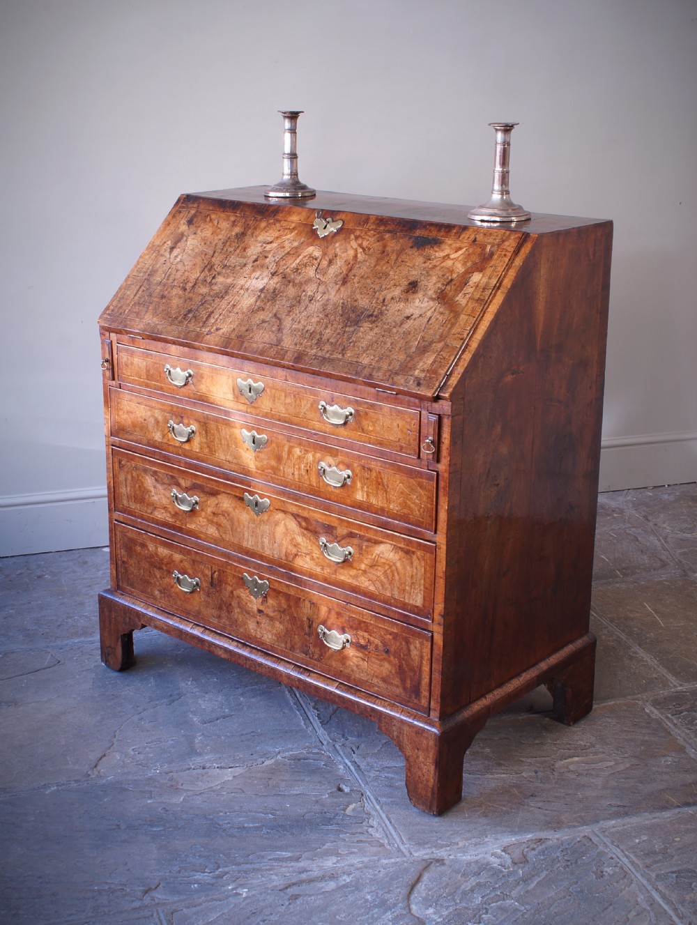 An 18th-century George II walnut bureau featuring a slant-front lid above four graduated drawers with brass handles, supported by bracket feet. View XVII