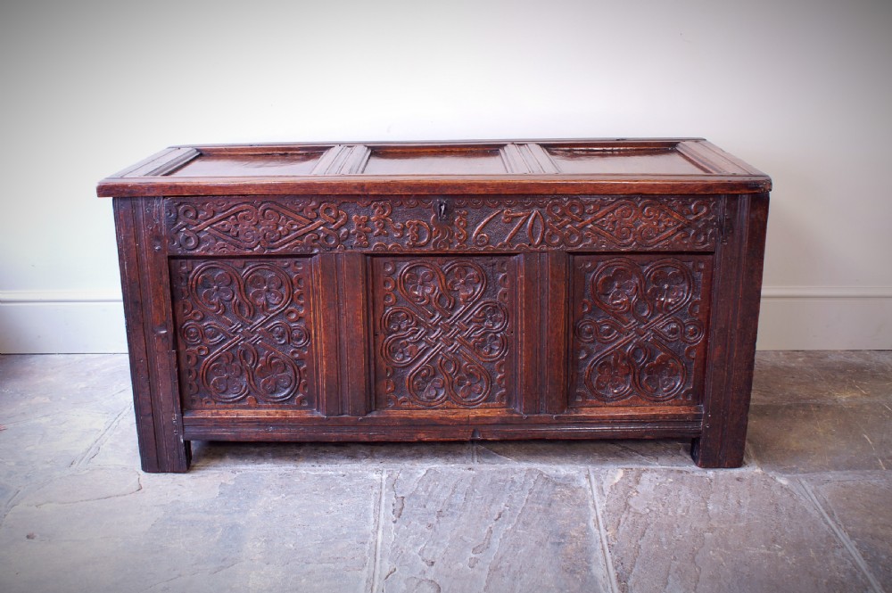A 17th-century dark carved oak joined coffer featuring intricate carved panels and a carved date of 1670 across the top frieze.
