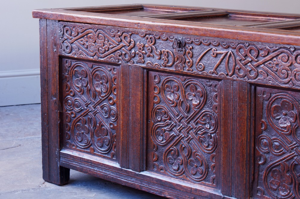 A 17th-century dark carved oak joined coffer featuring intricate carved panels and a carved date of 1670 across the top frieze. View II