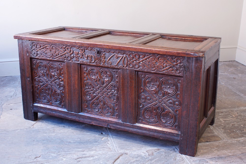 A 17th-century dark carved oak joined coffer featuring intricate carved panels and a carved date of 1670 across the top frieze. View III