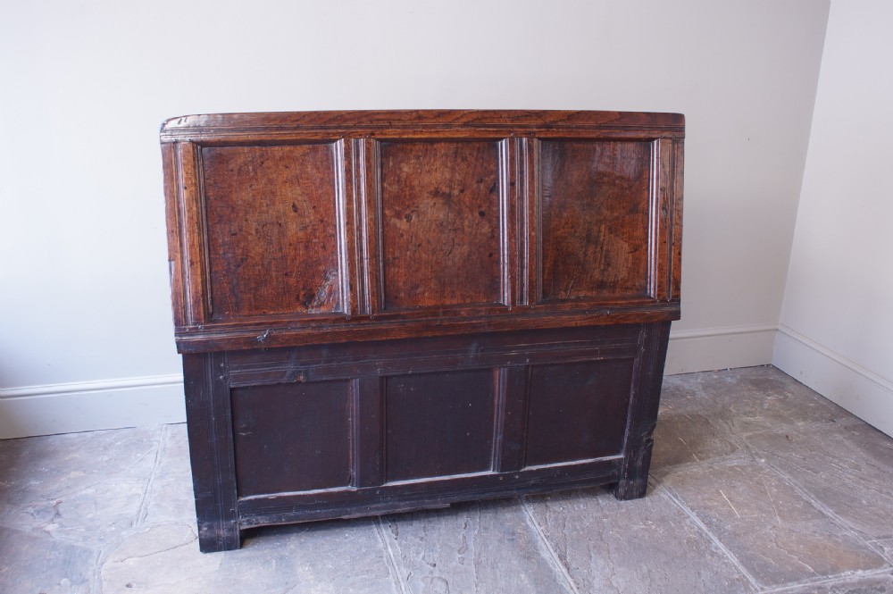 A 17th-century dark carved oak joined coffer featuring intricate carved panels and a carved date of 1670 across the top frieze. View V