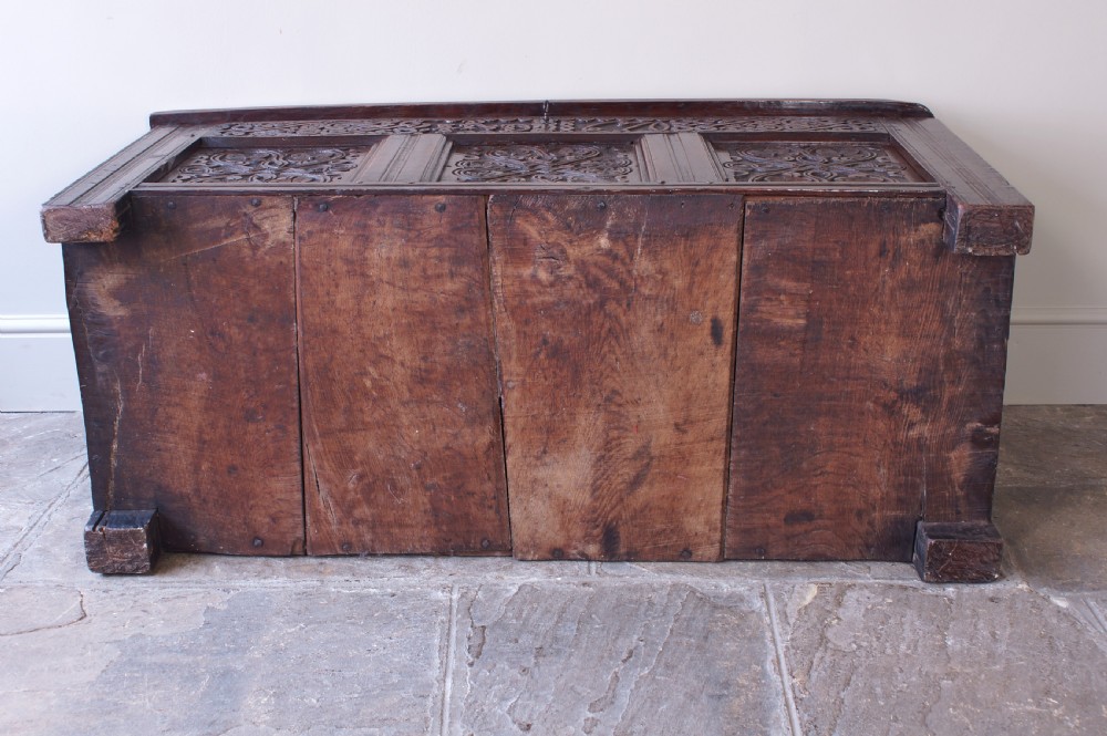 A 17th-century dark carved oak joined coffer featuring intricate carved panels and a carved date of 1670 across the top frieze. View VI