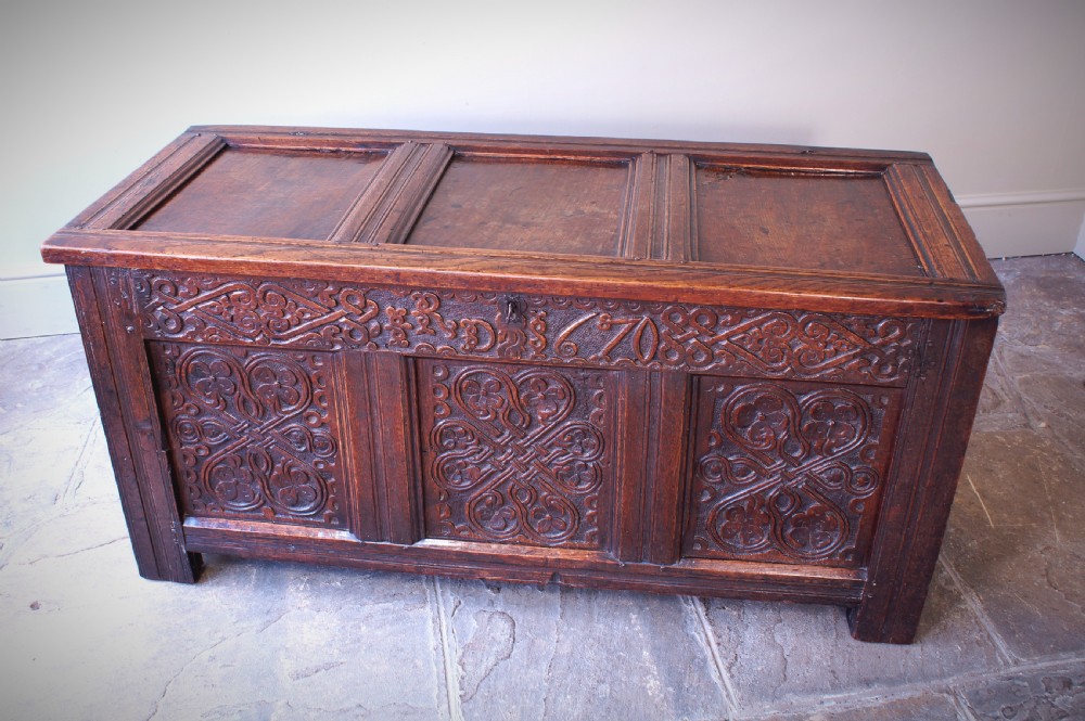 A 17th-century dark carved oak joined coffer featuring intricate carved panels and a carved date of 1670 across the top frieze. View VIII