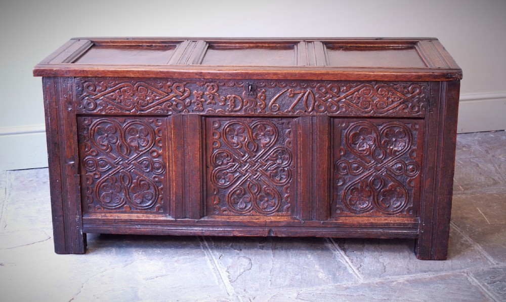 A 17th-century dark carved oak joined coffer featuring intricate carved panels and a carved date of 1670 across the top frieze. View IX