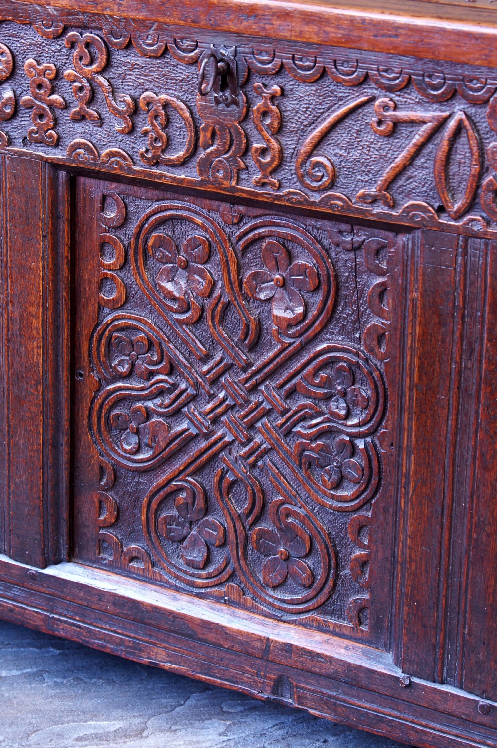 A 17th-century dark carved oak joined coffer featuring intricate carved panels and a carved date of 1670 across the top frieze. View X