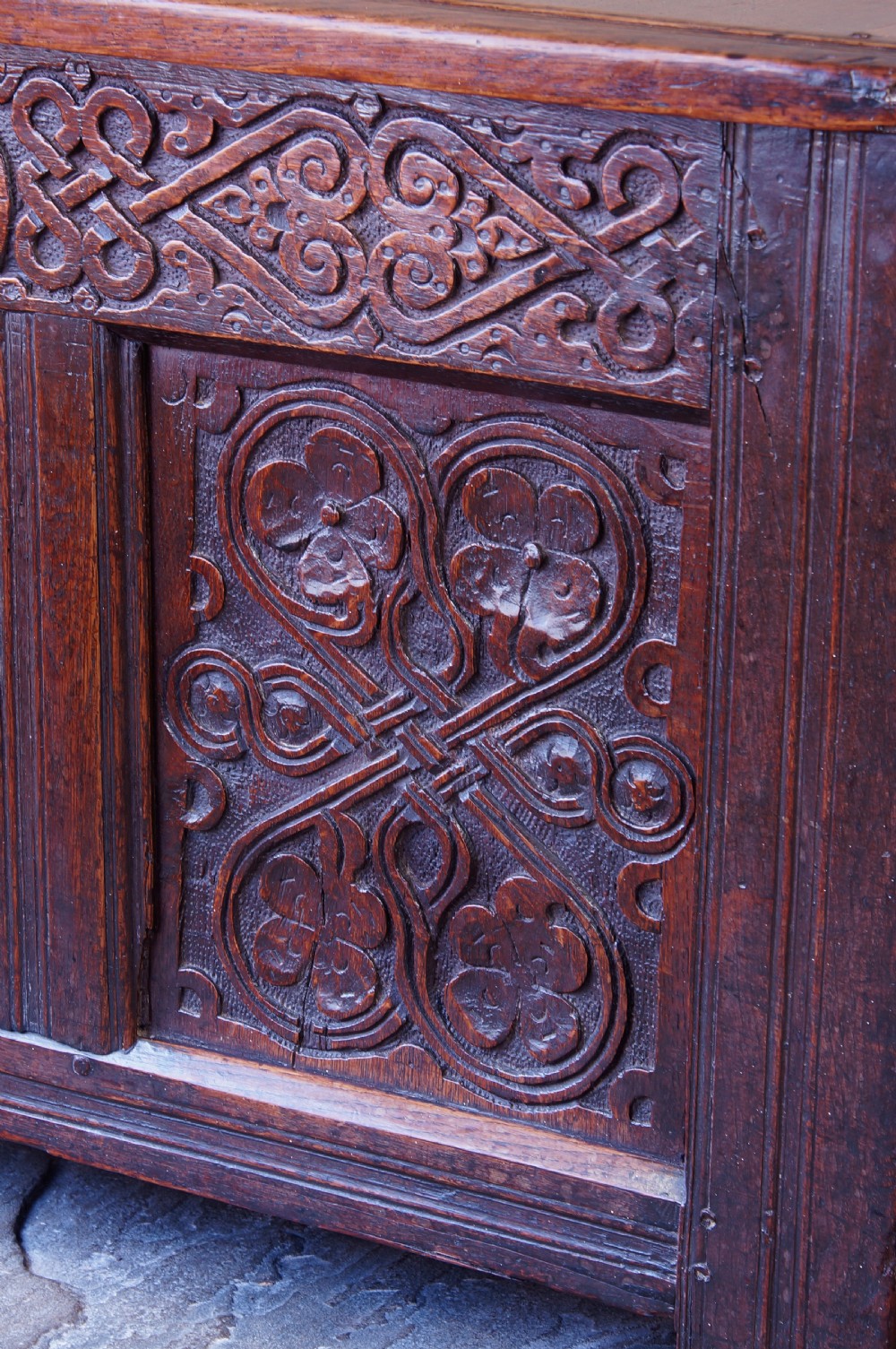 A 17th-century dark carved oak joined coffer featuring intricate carved panels and a carved date of 1670 across the top frieze. View XI