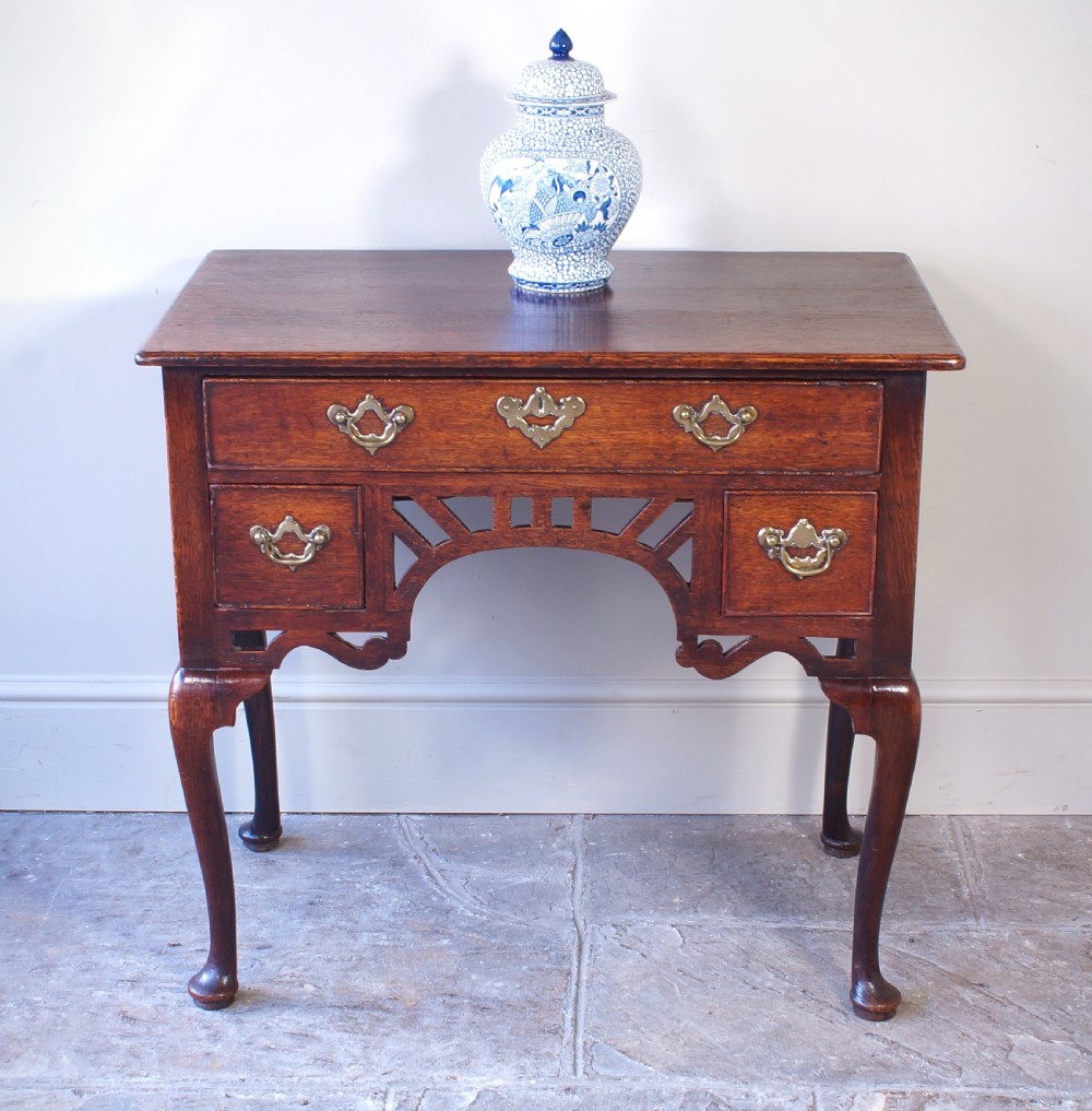 An 18th-century oak lowboy side table featuring cabriole legs, multiple drawers with brass swing handles, and an arched apron detail. View II