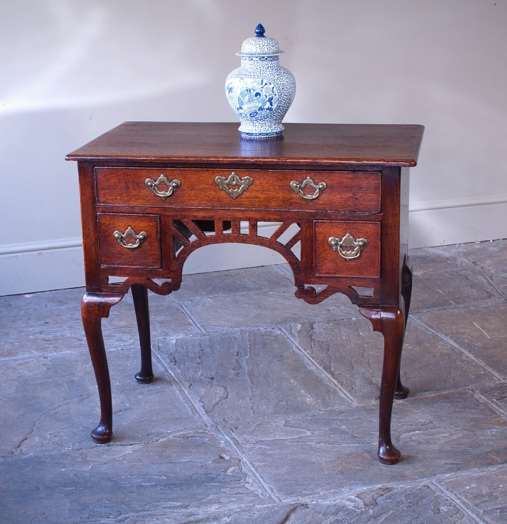 An 18th-century oak lowboy side table featuring cabriole legs, multiple drawers with brass swing handles, and an arched apron detail. View VIII