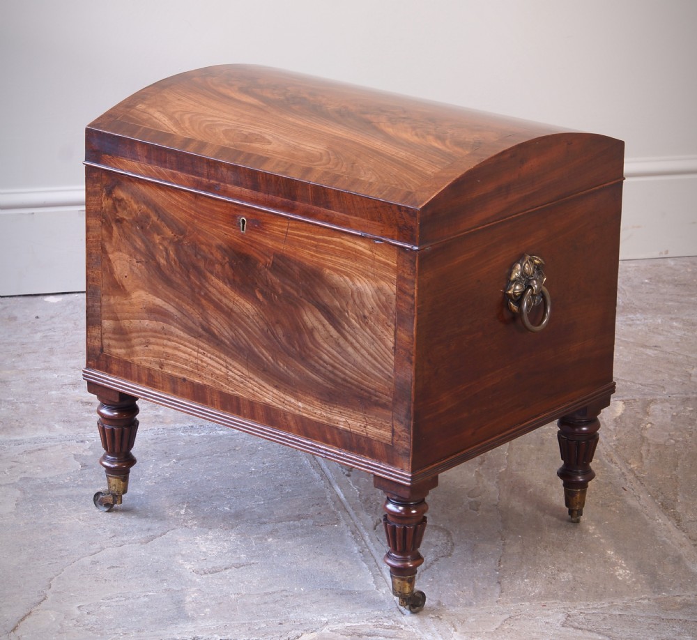 An open early 19th-century Regency flame mahogany cellarette featuring turned reeded legs, brass castors, side ring handles, and internal glass decanters. View II