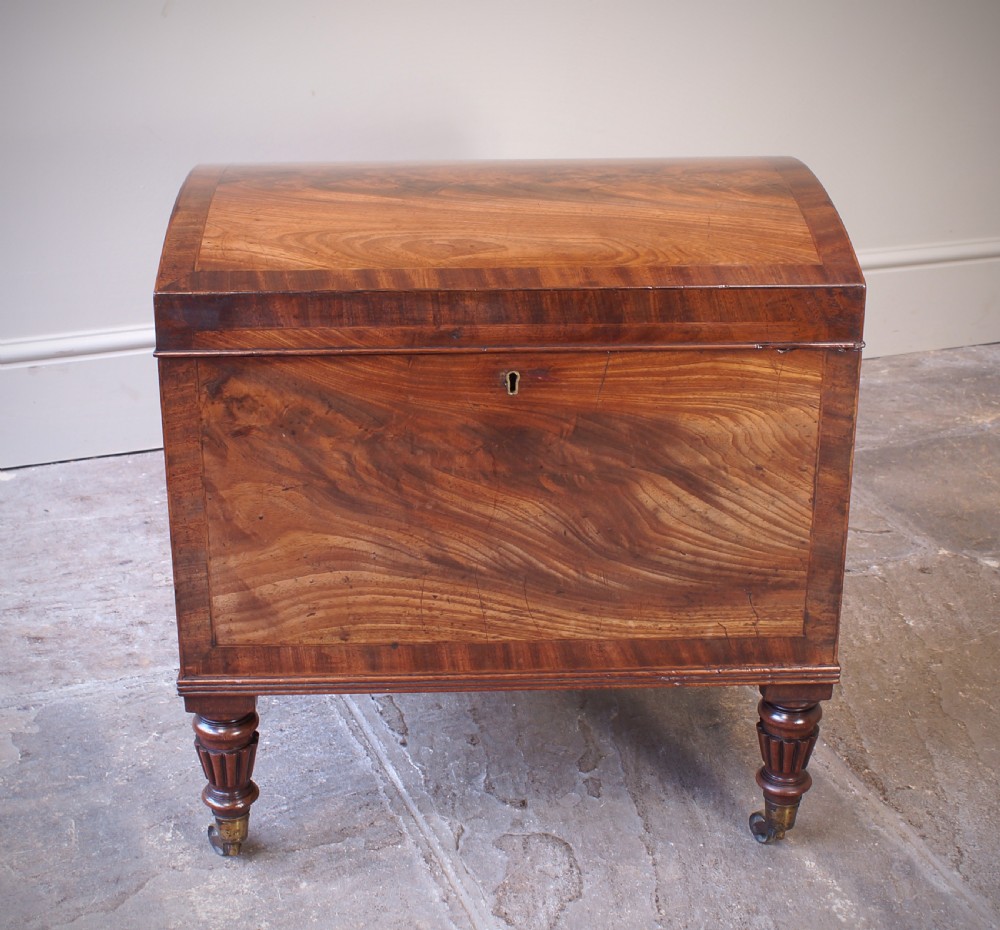 An open early 19th-century Regency flame mahogany cellarette featuring turned reeded legs, brass castors, side ring handles, and internal glass decanters. View IV