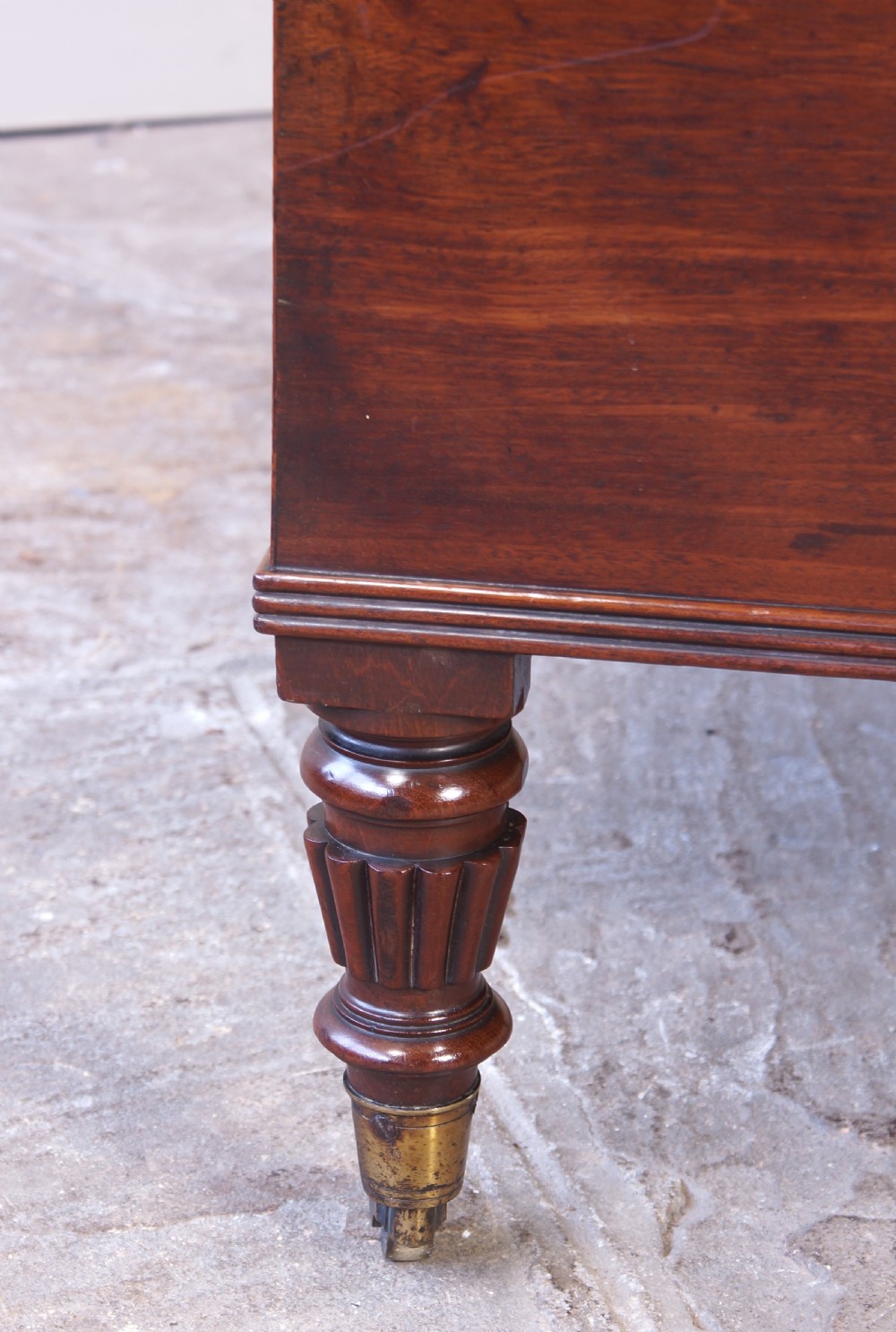 An open early 19th-century Regency flame mahogany cellarette featuring turned reeded legs, brass castors, side ring handles, and internal glass decanters. View V