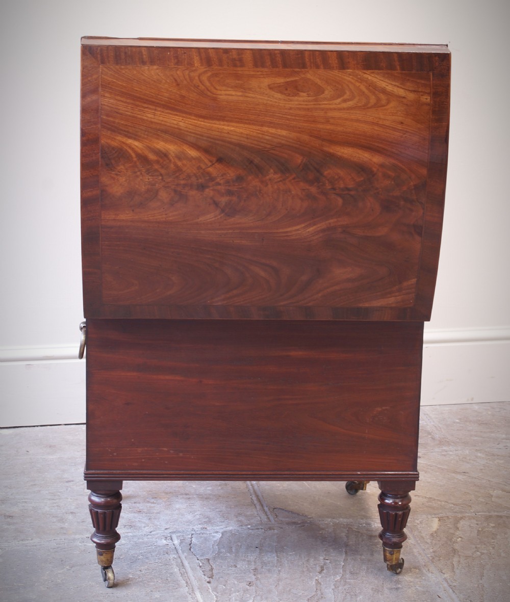An open early 19th-century Regency flame mahogany cellarette featuring turned reeded legs, brass castors, side ring handles, and internal glass decanters. View VII