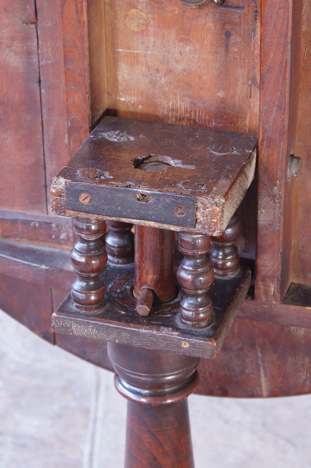 An 18th-century circular elm tilt-top tripod table shown with its top upright on a turned central column and three cabriole legs. View IX