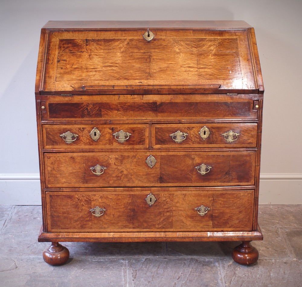 An early 18th-century walnut writing bureau featuring a sloping drop-front lid, brass drop handles, and turned bun feet. View II