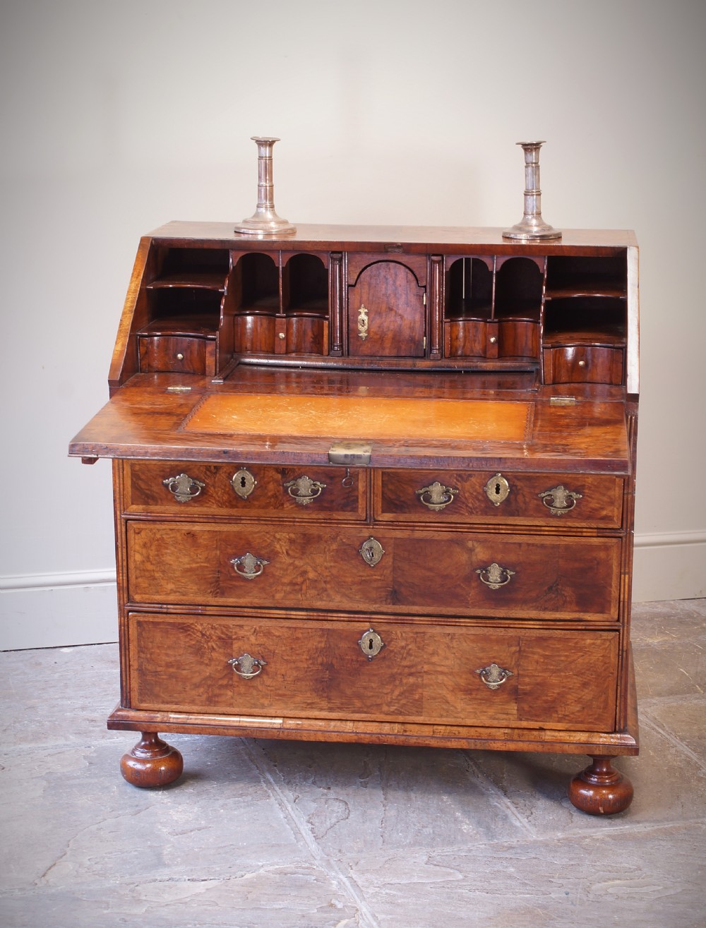 An early 18th-century walnut writing bureau featuring a sloping drop-front lid, brass drop handles, and turned bun feet. View VIII