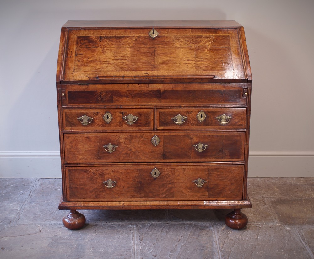 An early 18th-century walnut writing bureau featuring a sloping drop-front lid, brass drop handles, and turned bun feet. View XII