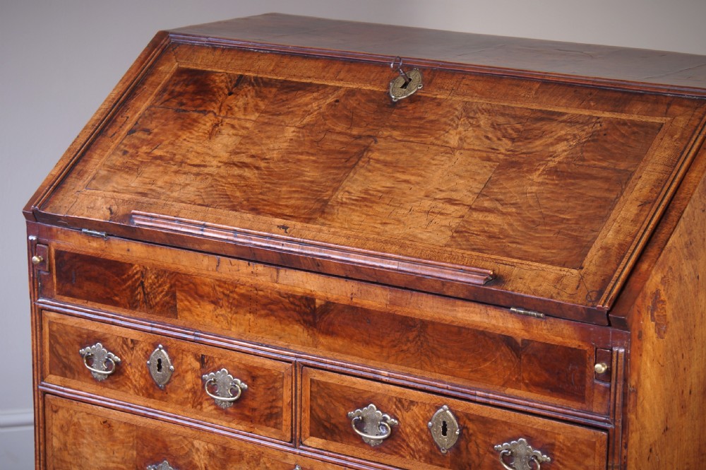 An early 18th-century walnut writing bureau featuring a sloping drop-front lid, brass drop handles, and turned bun feet. View XIII