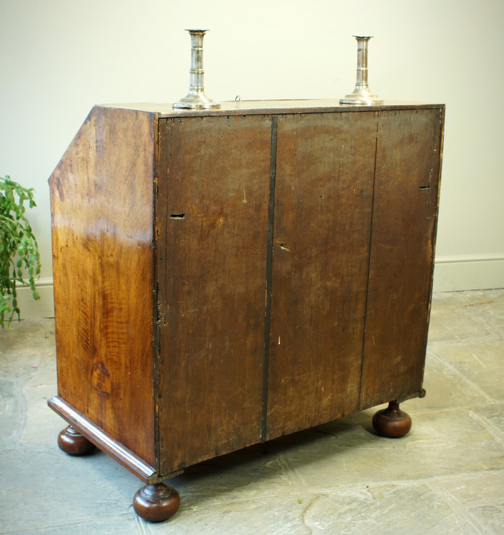 An early 18th-century walnut writing bureau featuring a sloping drop-front lid, brass drop handles, and turned bun feet. View XVII