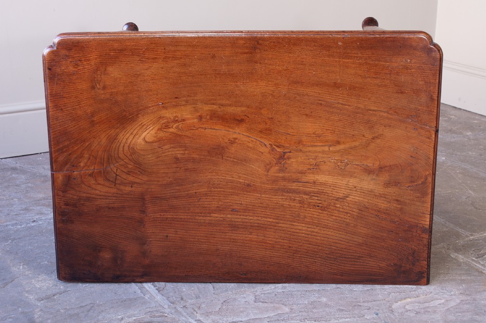 An 18th-century dark brown elm lowboy side table featuring three drawers with brass handles, a shaped apron, and four slender tapered legs ending in pad feet. View V