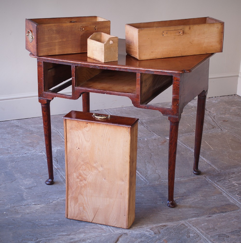 An 18th-century dark brown elm lowboy side table featuring three drawers with brass handles, a shaped apron, and four slender tapered legs ending in pad feet. View IX