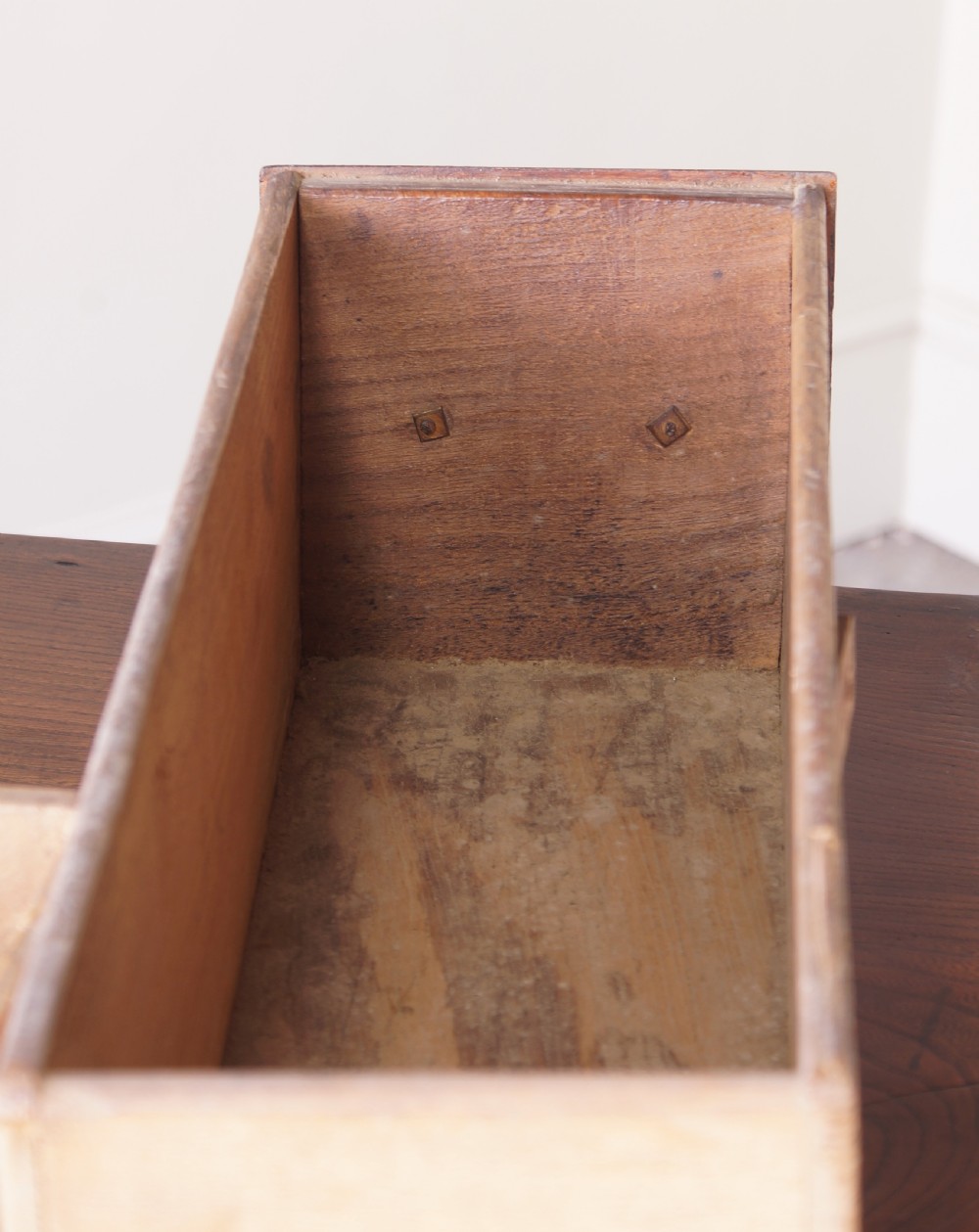 An 18th-century dark brown elm lowboy side table featuring three drawers with brass handles, a shaped apron, and four slender tapered legs ending in pad feet. View XI