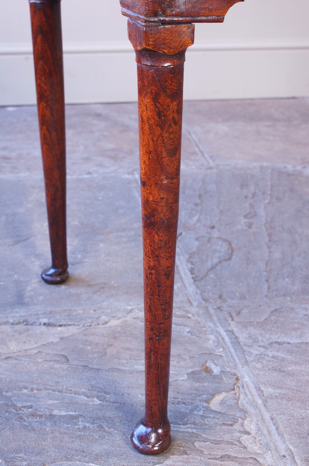 An 18th-century dark brown elm lowboy side table featuring three drawers with brass handles, a shaped apron, and four slender tapered legs ending in pad feet. View XII