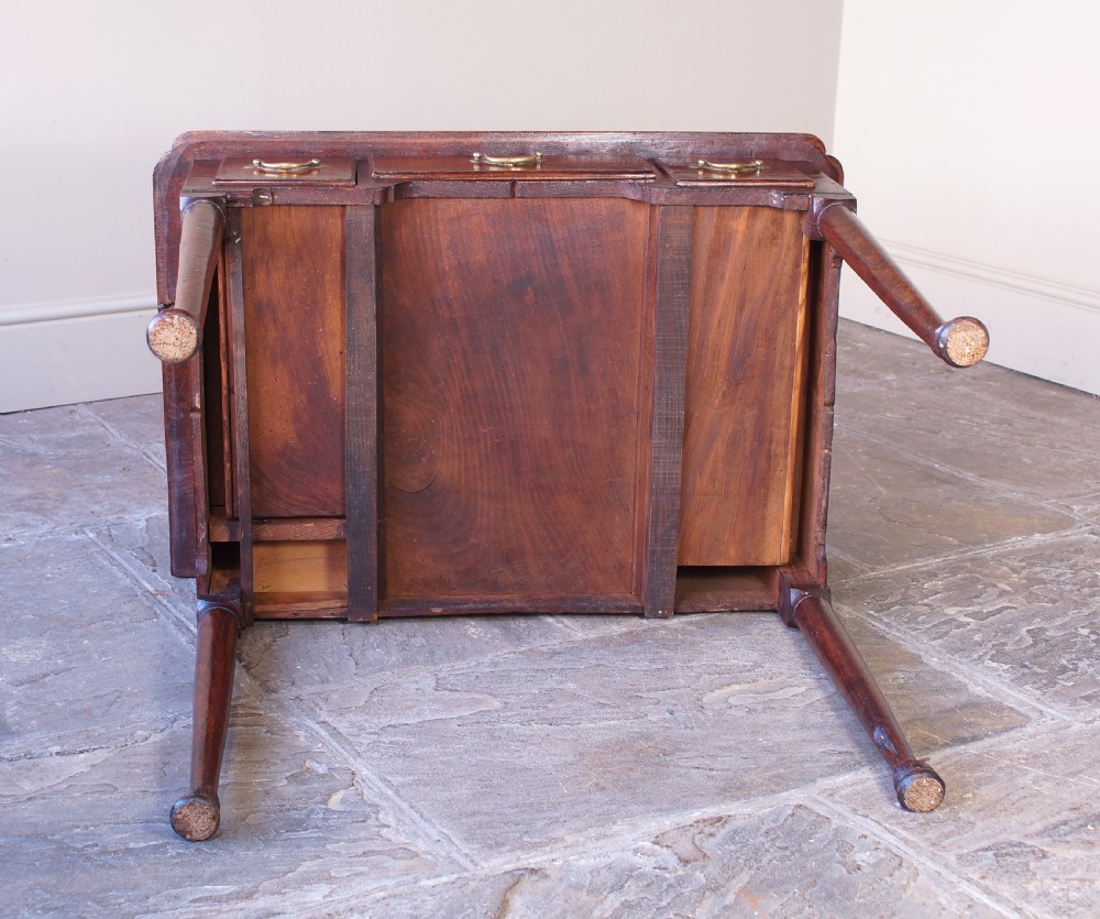 An 18th-century dark brown elm lowboy side table featuring three drawers with brass handles, a shaped apron, and four slender tapered legs ending in pad feet. View XIII