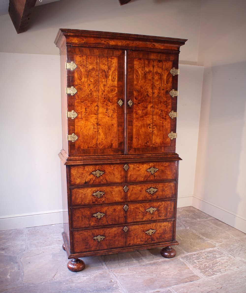 An early eighteenth-century burr walnut cabinet on chest featuring double upper doors with brass strap hinges above four graduated drawers, resting on turned bun feet. View II