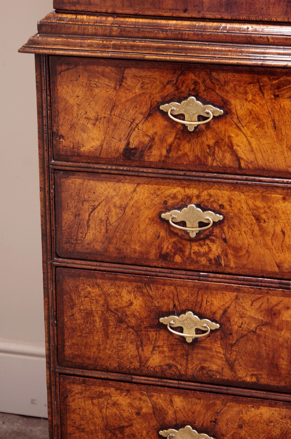 An early eighteenth-century burr walnut cabinet on chest featuring double upper doors with brass strap hinges above four graduated drawers, resting on turned bun feet. View III