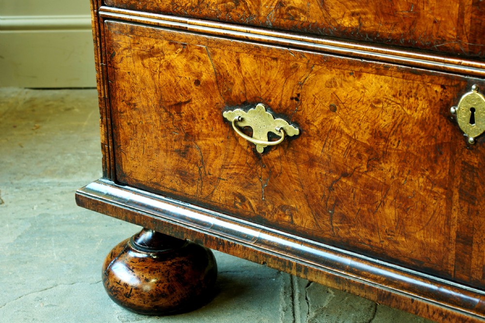 An early eighteenth-century burr walnut cabinet on chest featuring double upper doors with brass strap hinges above four graduated drawers, resting on turned bun feet. View XI