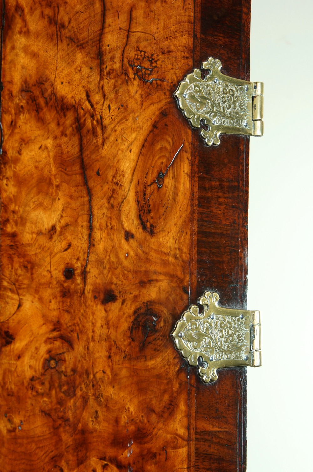 An early eighteenth-century burr walnut cabinet on chest featuring double upper doors with brass strap hinges above four graduated drawers, resting on turned bun feet. View XVI