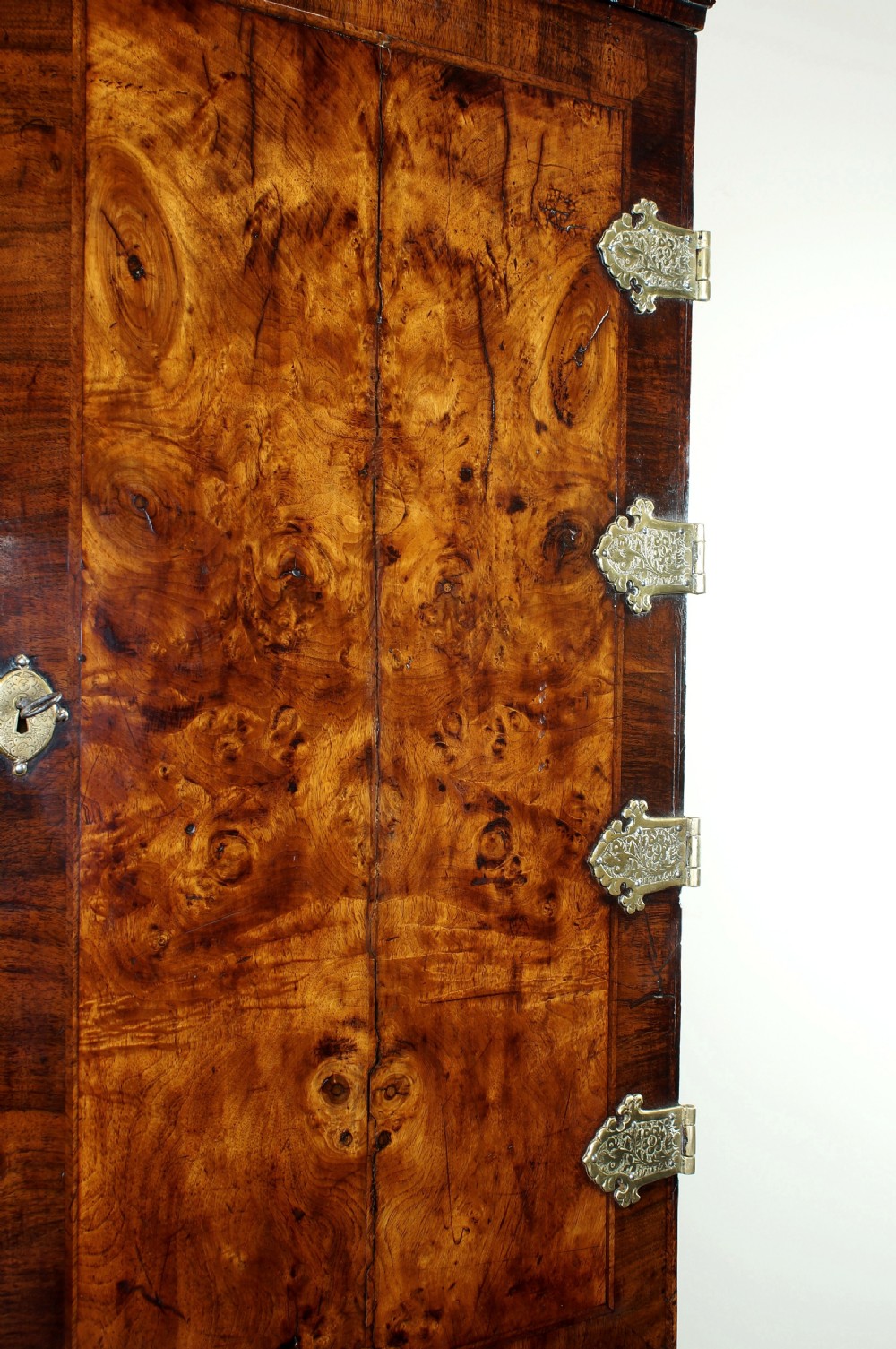An early eighteenth-century burr walnut cabinet on chest featuring double upper doors with brass strap hinges above four graduated drawers, resting on turned bun feet. View XVIII